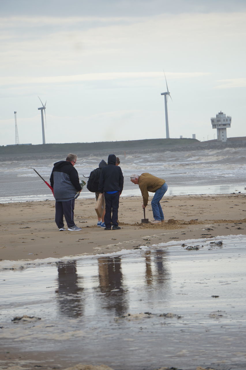 REAR VIEW OF PEOPLE WITH DOG ON BEACH