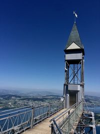 Tower by mountains against clear blue sky