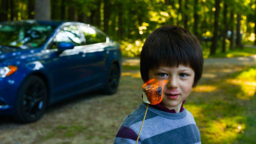 Portrait of boy looking at fire while standing near car