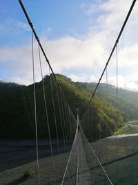 View of suspension bridge against cloudy sky