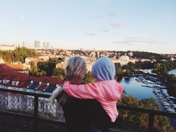 Rear view of mother carrying daughter against cityscape