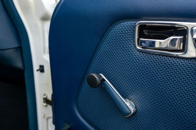 Detail view of a car door with a window crank handle