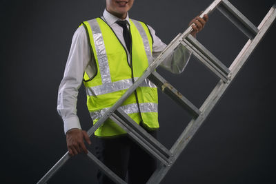 Man holding umbrella while standing against black background