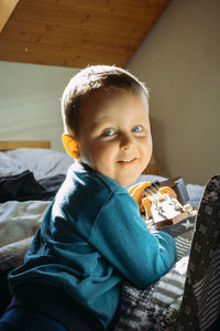 Portrait of cute boy sitting on bed at home