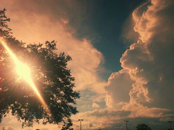 Low angle view of sun streaming through clouds