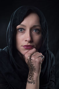 Close-up portrait of young woman with henna tattoo on hand
