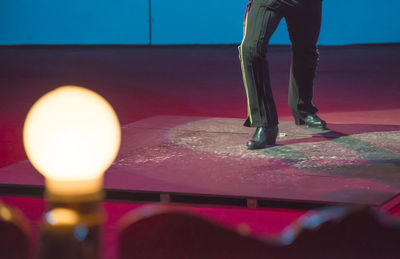 Low section of woman standing by illuminated lamp