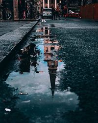 Reflection of people in puddle on road