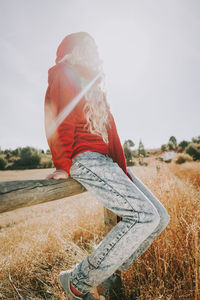 Midsection of woman sitting on field against sky