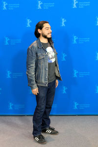 Young man standing against blue wall