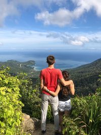 Rear view of couple standing on cliff against sea at ko phangan