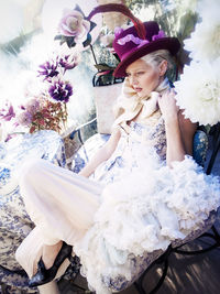 Woman in dress looking away while sitting on chair