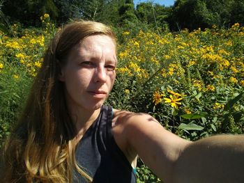 Portrait of woman against yellow flowers on field