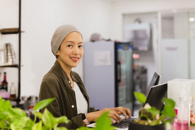 Woman restaurant owner standing behind the counter and using laptop while working.