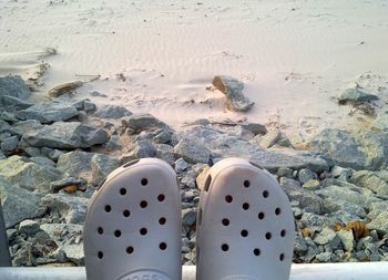 Close-up of shoes against rocks at beach