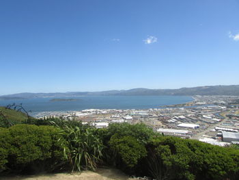 Scenic view of town by sea against clear blue sky