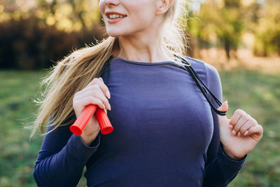 Cropped look, girl holding a skipping rope around her neck.