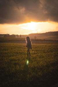 Woman on field against sky during sunset