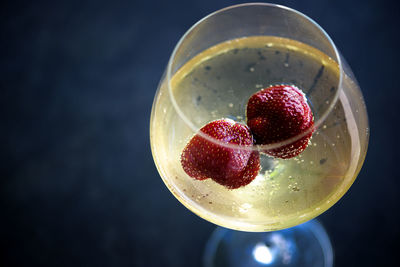 Top view on glass  chilled cold white wine with strawberries on blue swimming pool water background