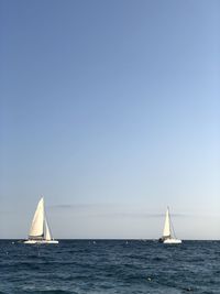 Sailboat sailing in sea against clear sky