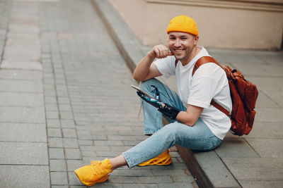 Portrait of smiling man sitting on footpath