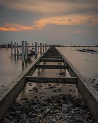 Pier over sea against sky during sunset