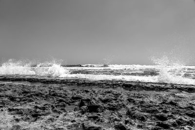Waves splashing on shore against sky