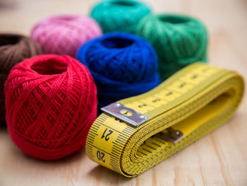 Close-up of tape measure and multi colored wool ball on table