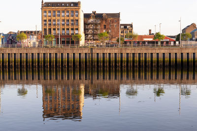 Reflection of buildings in lake against sky in city