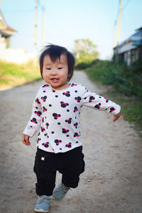 Portrait of cute girl standing on footpath