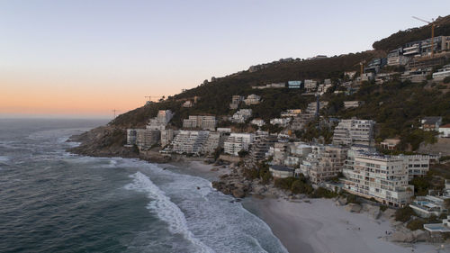 Buildings by sea against clear sky