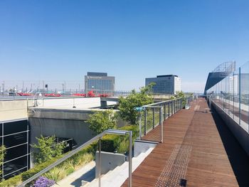 Footpath amidst buildings in city against clear blue sky