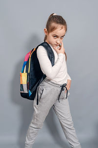 Little girl with backpack. schoolgirl with backpack looks seriously and frowning. problems at school