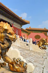 Statues at temple outside building against sky