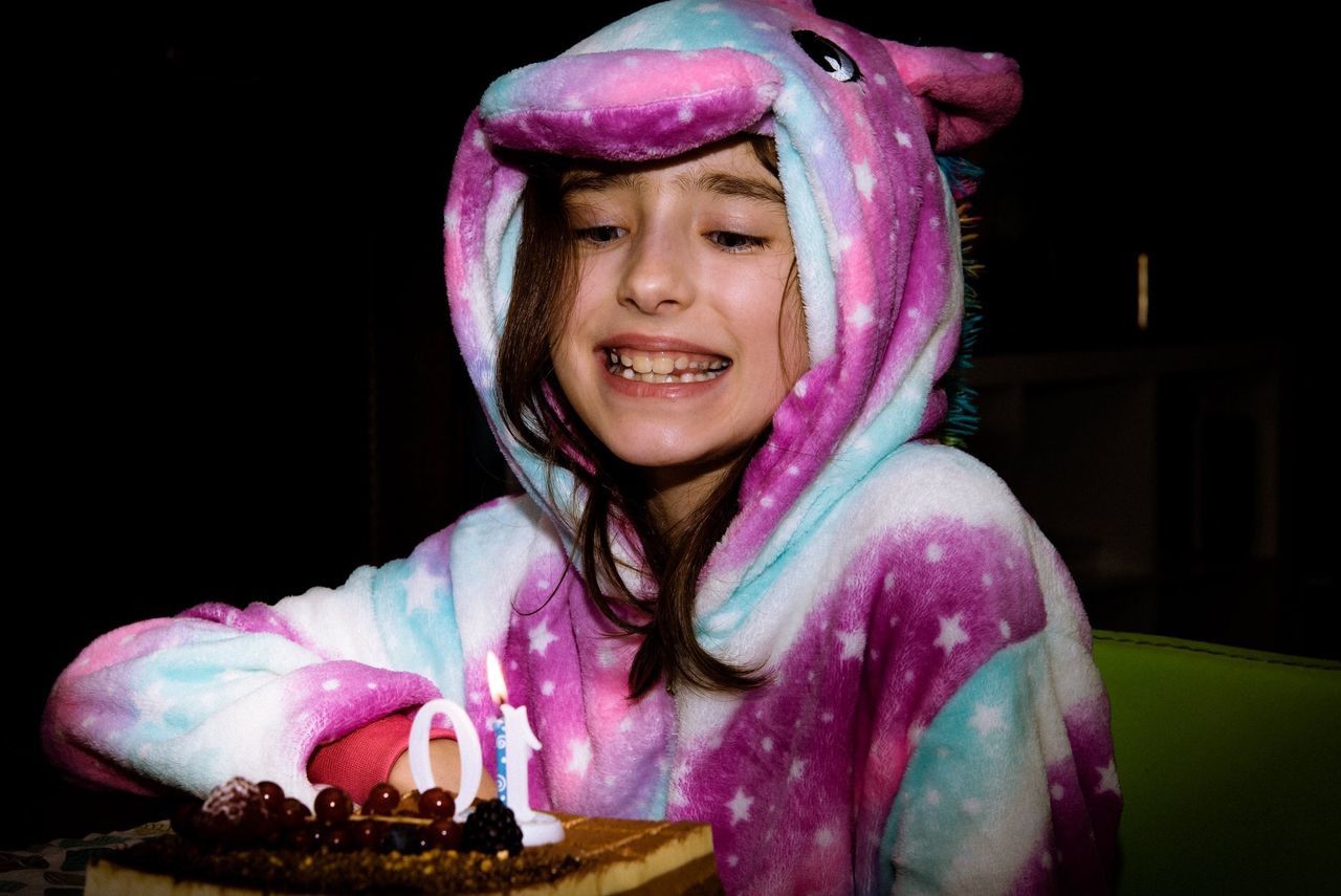 headshot, front view, smiling, food, portrait, one person, girls, food and drink, lifestyles, women, happiness, child, indoors, childhood, emotion, leisure activity, real people, pink color, innocence, black background, pre-adolescent child