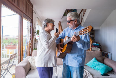 Men playing guitar on sofa