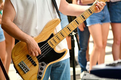 Midsection of man playing guitar while standing outdoors