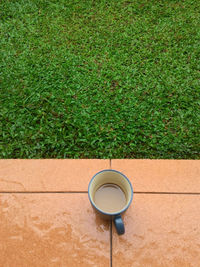 High angle view of coffee cup on porch by field