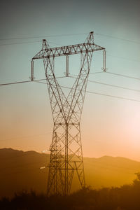 Low angle view of silhouette electricity pylon against sky during sunset