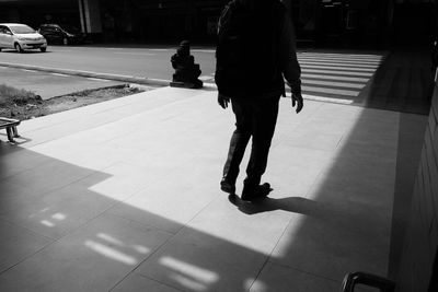 Low section of man walking on footpath in city