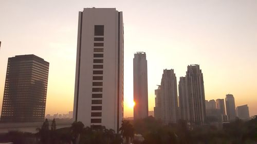 Modern buildings in city against sky during sunset