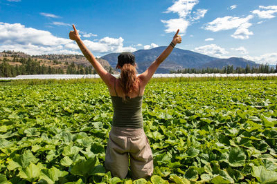 Rear view of man standing on field against sky