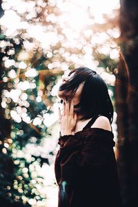 Woman standing by tree against plants