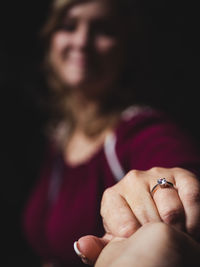 Close-up of woman showing wedding ring against black background