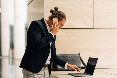 Businessman using laptop while talking on phone