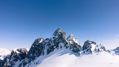 Scenic view of snow covered mountains against clear blue sky