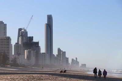 People at beach against buildings in city