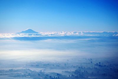 Aerial view of snowcapped mountains against blue sky