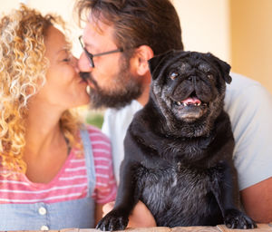 Portrait of dog against couple kissing at home