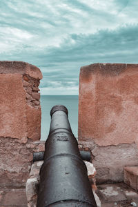 A cannon on the wall pointing at sea